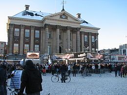 Glass house with sign and spectators, in front of city hall