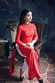 A woman wearing red Áo dài is sitting on a chair, December 2016