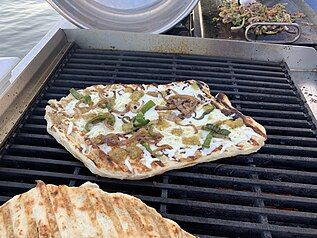 Pizza grilling on an outdoor gas range