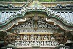 White carved figures under an undulating gable.