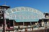 A faded blue, pink, and gold sign sits on the side of a rusting showboat and displays the words, "GOLDENROD / NATIONAL LANDMARK / SHOWBOAT / St. Charles, Missouri"