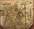 Ivory label depicting the pharaoh Den, found at his tomb in Abydos, c. 3000 BCE. Wepwawet is at the upper right atop a standard.