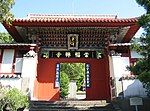 Small wooden gate painted in red, green and blue. Boards with Chinese characters are attached to the gate.