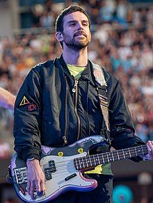 Berryman on stage with his bass, wearing a neon green shirt and a black jacket