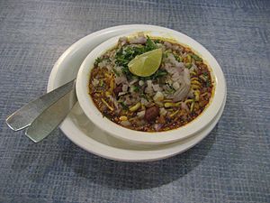 Image of misal served in a white bowl with garnished onion and slice of lemon on top of it.