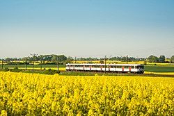 An EN57 passes through fields around the village