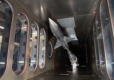 An AGARD-B model installed on a sting is shown in the test section of Supersonic Wind Tunnel A in the von Kármán Gas Dynamics Facility