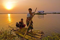 A women transporting a child and goats in a flooded part of the delta in Bangladesh.