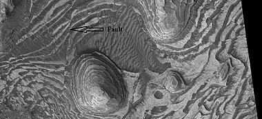 Layers and faults in Firsoff Crater, as seen by HiRISE under HiWish program. Arrows show one large fault, but there are other smaller ones in the picture.