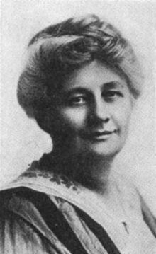 A smiling middle-aged white woman with greying hair in a bouffant updo