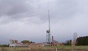 The same buildings with the water tower and electrical mast at right of center, and silos at left