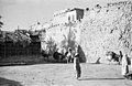 Locals stroll past Qatif Castle, highlighting its towering walls and ramparts.