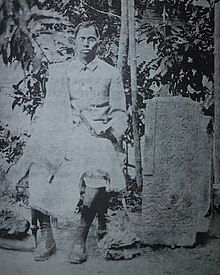 Choudhury seated next a stone fragment from the Pratapgarh Kingdom, c. 1900s.