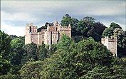 Upper sections of Dunster Cascastle walls and towers showing above trees.