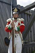 A Corporal of the 24th Regiment of Foot in ceremonial dress stands in front of the gate of Fort Ingall (reenactment).