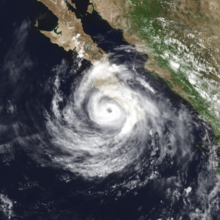 A photograph of a hurricane just off the southwestern coast of the Baja California peninsula; it has a well-defined eye surrounded by a small area of central convection and some spiral bands