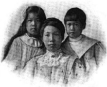 An Asian-American mother and her two children in a formal portrait; the daughter and son are about 11 and 9 years old, respectively; the daughter has long dark hair, the son has dark hair cut short with bangs; the mother's dark hair is in an updo, and she is wearing a high lace collar.