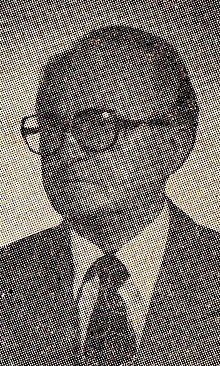 Headshot of a man in a suit and glasses