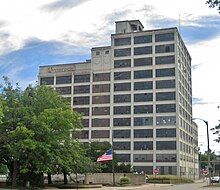 A 12-story building with some broken and rusted windows; a faded "Ameroch" logo is painted near the top