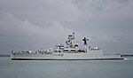 Long, grey ship against a cloudy sky