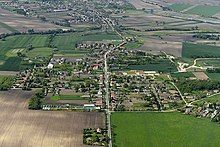 An aerial photo of Kisigmánd, a small village. The village is centred along a central road.