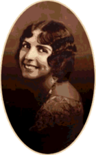 A studio photograph of a young woman looking over her shoulder.