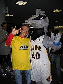 A person in a mascot costume dressed as Peter the Anteater performs the "Rip 'Em 'Eaters" hand signal (two middle fingers pinched with the thumb, with pinky and index finger sticking up as "ears") with a fan