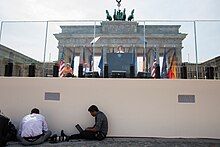 Photojournalists Evan Vucci and Jewel Samad work in the foreground as President Barack Obama delivers remarks at the Brandenburg Gate in Berlin, Germany, June 19, 2013. On stage with the President are Chancellor Angela Merkel and Berlin Mayor Klaus Wowereit. (Official White House Photo by Pete Souza)