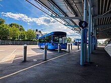 A two-tone blue single deck bus parked in an empty bus station.