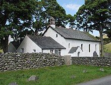 A tiny white church surrounded by a stone wall