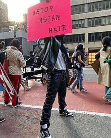 A demonstrator holding a Stop Asian Hate banner