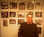 A middle-aged, bespecatacled man smiles in front of a wall covered with New York Cosmos memorabilia