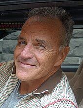 A closeup of a man with grey hair sitting in a car.