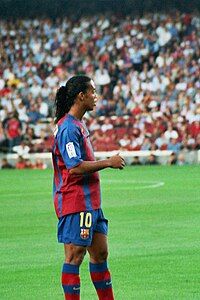 Isolated football player on the pitch, wearing the number 10 jersey. Vaguely smiling.