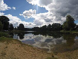 A photo of Kose Valgjärv showing the lake reflecting white clouds overhead