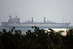 Long, grey ship seen through foliage