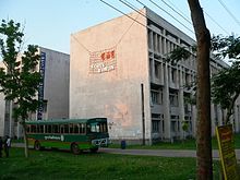 Plain concrete building, with a green bus outside