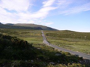 the road slowly rises up a grass-covered mountain area