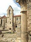 View of the ruined cloisters and South façade of the church with rose window and bell tower.