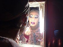 A drag queen putting on lip liner