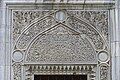 An intricately carved marble tympanum above an exterior window of the mosque