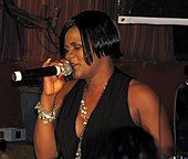 A color photograph of Lady Saw, who is performing live in a microphone.