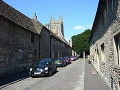 Street of gray stone houses. The church tower can be seen n the background