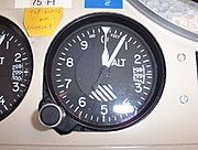 Aircraft altimeter set at 75 ft (23 m) showing a pressure of 29.87 in (1011.5 hPa). This altimeter is mounted in a console at a radio station.