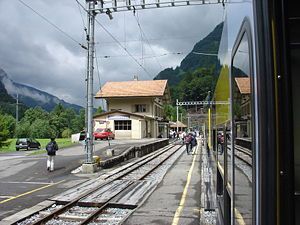 Three-story station building with gabled roof viewed from parked train