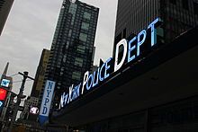 A glowing blue NYPD Times Square sign with the initial letters in white