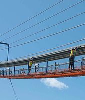 Inspectors dampening wind induced strand movement to allow strand measurements.