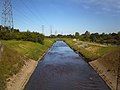 A canalised section of the Tame in Sandwell Valley, showing Forge Mill Lake to the right, separated from the river by a steep embankment.