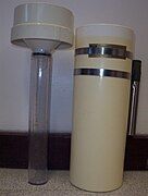 Standard rain gauge. On the right can be seen a overflow catch with a metal pipe that fits over a metal post in the ground. On the left is the funnel with the graduated cylinder attached.