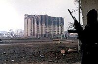 A Chechen fighter stands near the government palace building during a short lull in fighting in Grozny, Chechnya.